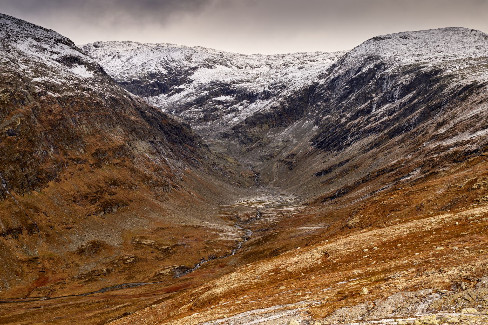 Breathtaking winter scene of a snowy mountain valley in Norway's rugged wilderness.