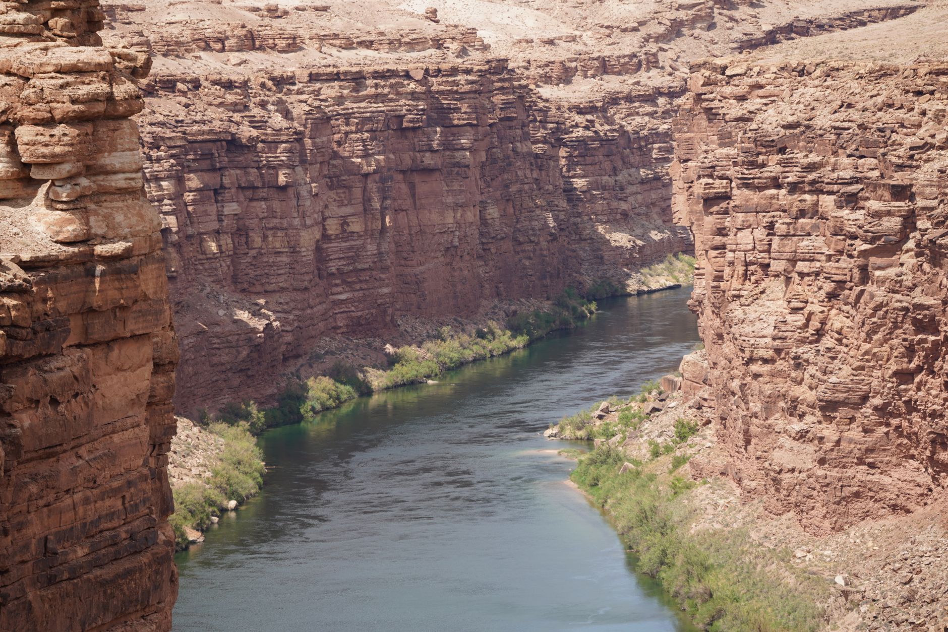 A beautiful view of a river carving through towering brown rock formations under a clear sky.