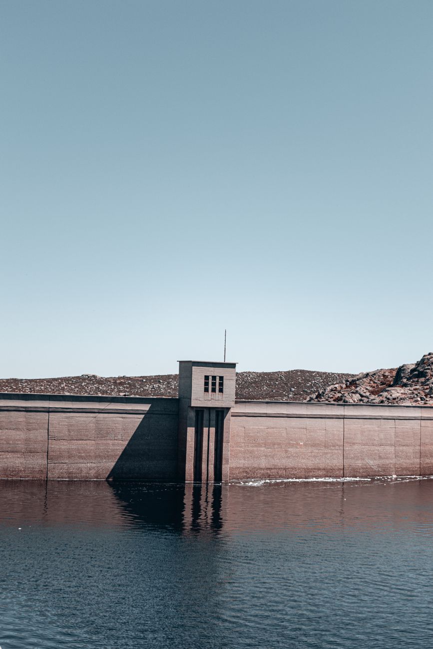 Tranquil view of a dam with a water reservoir under a clear blue sky.